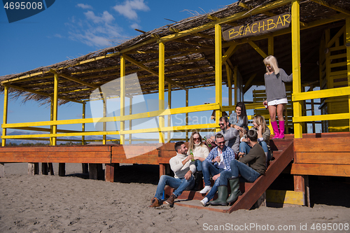 Image of Group of friends having fun on autumn day at beach