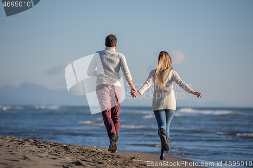 Image of Loving young couple on a beach at autumn sunny day