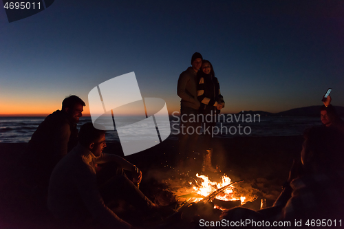 Image of Friends having fun at beach on autumn day