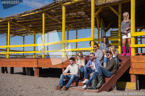 Image of Group of friends having fun on autumn day at beach