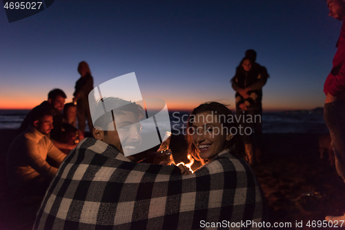 Image of Couple enjoying with friends at sunset on the beach