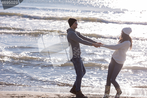 Image of Loving young couple on a beach at autumn sunny day