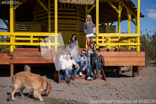 Image of Group of friends having fun on autumn day at beach