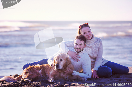 Image of Couple with dog enjoying time on beach