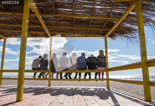 Image of Group of friends having fun on autumn day at beach