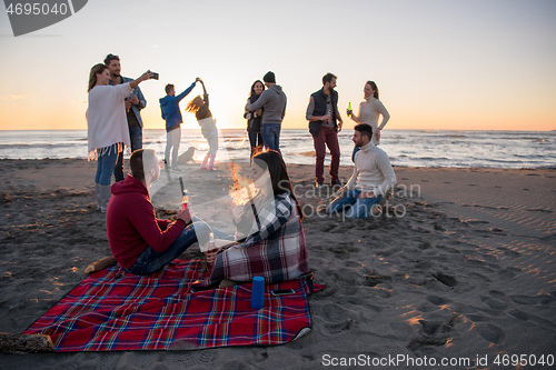 Image of Couple enjoying with friends at sunset on the beach