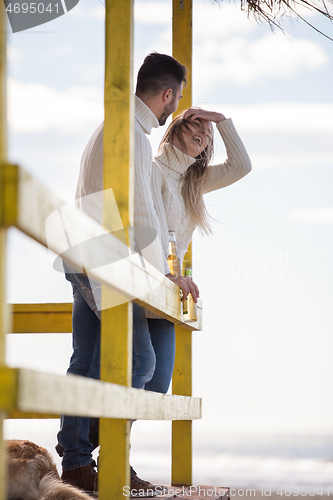 Image of young couple drinking beer together at the beach