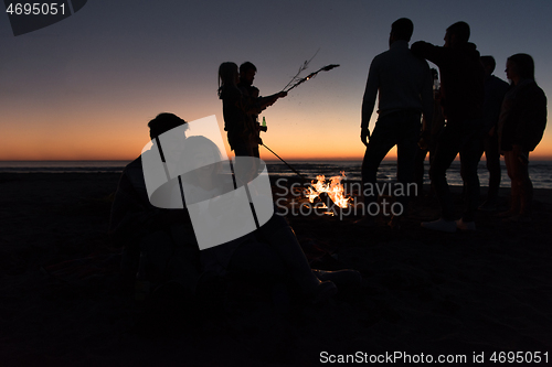 Image of Couple enjoying bonfire with friends on beach