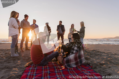 Image of Couple enjoying with friends at sunset on the beach