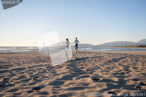 Image of couple with dog having fun on beach on autmun day