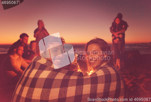 Image of Couple enjoying with friends at sunset on the beach