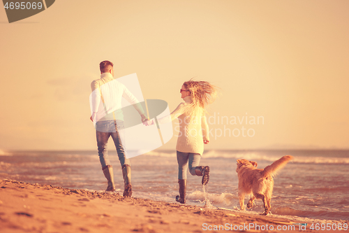 Image of couple with dog having fun on beach on autmun day