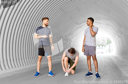 Image of male friends with earphones training outdoors