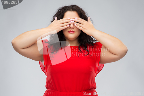 Image of woman in red dress closing her eyes by hands