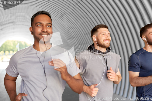 Image of male friends with earphones running outdoors