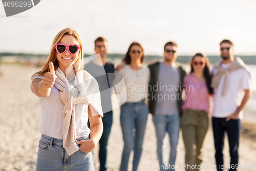 Image of woman with friends on beach showing thumbs up