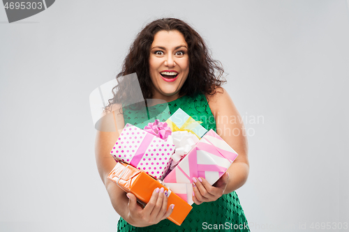 Image of happy woman in green dress holding gift boxes