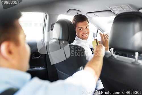 Image of male car driver taking credit card from passenger