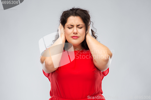 Image of woman in red dress closing her ears by hands