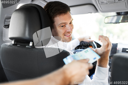Image of male car driver taking money from passenger
