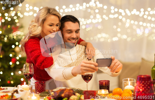 Image of happy couple taking selfie at christmas dinner