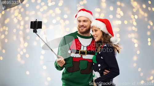 Image of happy couple in christmas sweaters taking selfie