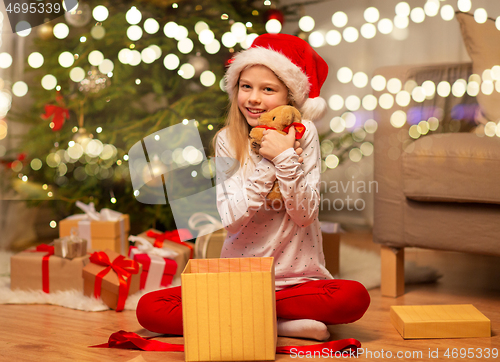 Image of smiling girl in santa hat with christmas gift