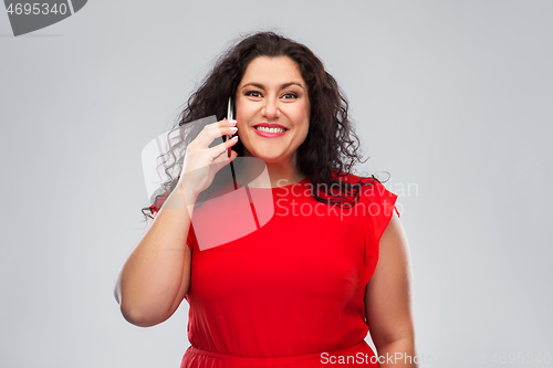 Image of smiling woman in red dress calling on smartphone