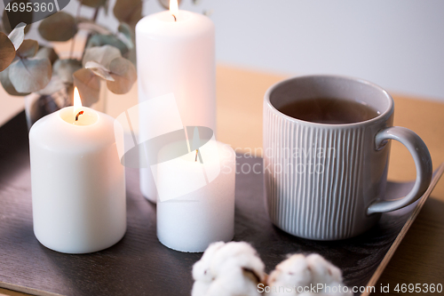 Image of candles, tea and branches of eucalyptus on table