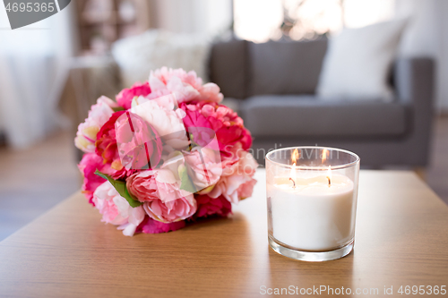 Image of burning fragrance candle and flower bunch at home