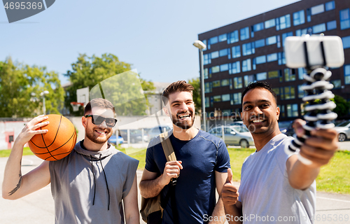 Image of happy men taking selfie at basketball playground