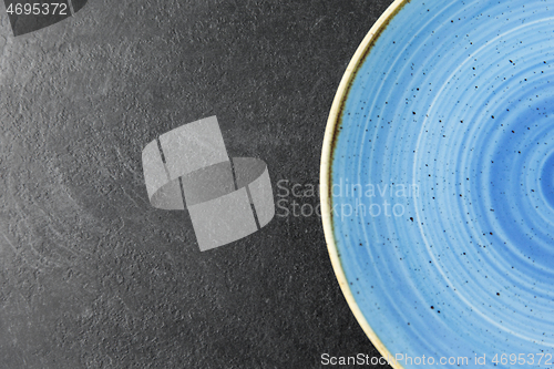 Image of close up of blue ceramic plate on slate background