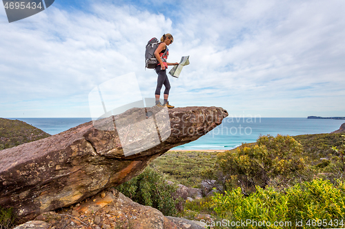 Image of Hiker on a rock precipice holding a map