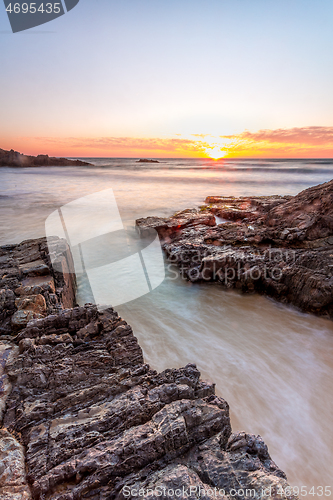 Image of Shore waves rushing up the rock channel at sunrise