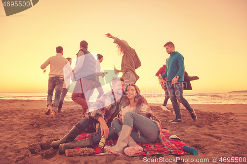 Image of Couple enjoying with friends at sunset on the beach