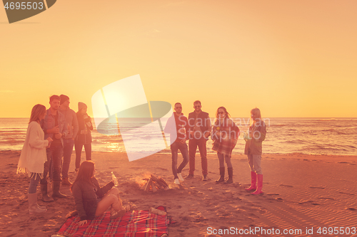 Image of Friends having fun at beach on autumn day