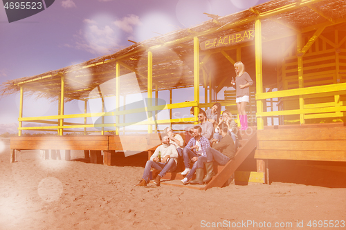 Image of Group of friends having fun on autumn day at beach