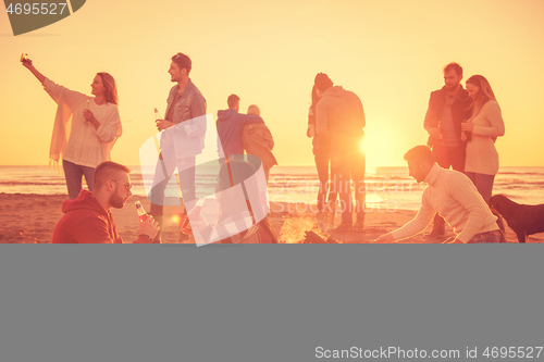 Image of Couple enjoying with friends at sunset on the beach