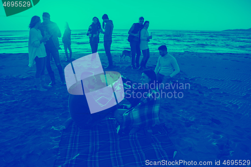 Image of Couple enjoying with friends at sunset on the beach