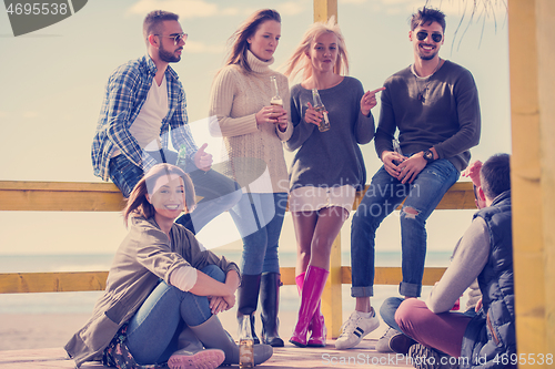 Image of Group of friends having fun on autumn day at beach