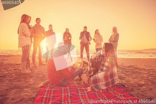 Image of Couple enjoying with friends at sunset on the beach