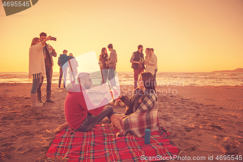 Image of Couple enjoying with friends at sunset on the beach