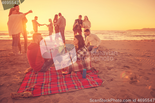 Image of Couple enjoying with friends at sunset on the beach