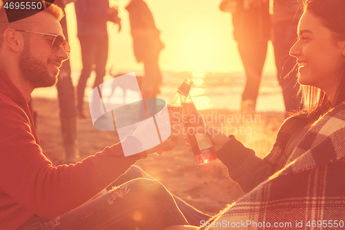 Image of Couple enjoying with friends at sunset on the beach