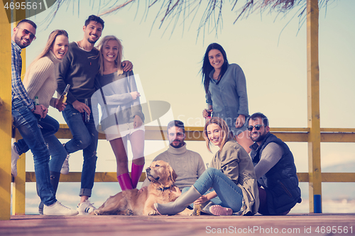 Image of Group of friends having fun on autumn day at beach