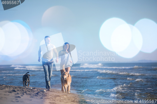 Image of couple with dog having fun on beach on autmun day