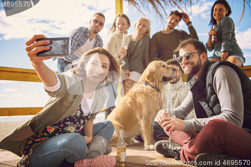 Image of Group of friends having fun on autumn day at beach