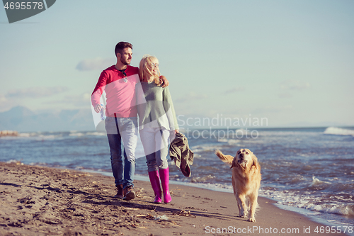 Image of couple with dog having fun on beach on autmun day