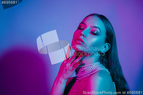 Image of High Fashion model in colorful bright neon lights posing at studio