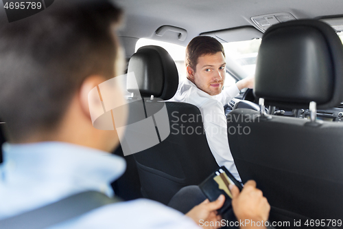 Image of male car driver looking at passenger with wallet